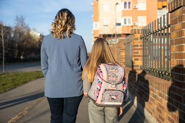 A tender moment captured from behind as a mother and daughter share a quiet walk, showcasing their...