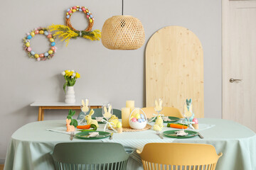 Festive table setting with Easter rabbits and eggs in kitchen