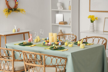Beautiful table setting with decorative bunnies and Easter eggs in dining room