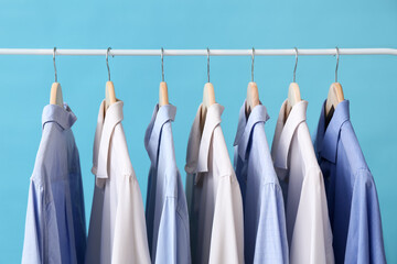 Rack with stylish collar shirts on blue background