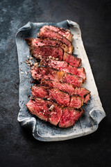 Traditional barbecue dry aged Wagyu rib eye beef steak with salt and pepper sliced and served as close-up on a design plate