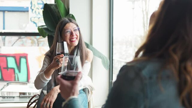 Smiling mature friends are toasting with glasses of red wine, enjoying a cheerful meeting at a restaurant