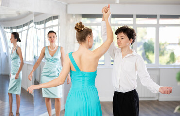 Young couple of teenagers in evening dresses are learning to dance an polonaise dance