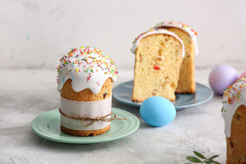 Plates with sweet Easter cakes and painted eggs on grey table
