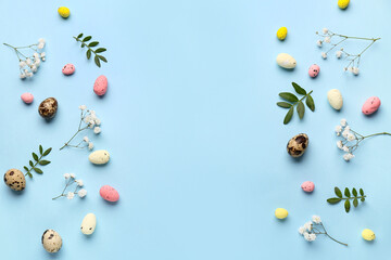 Frame made of flowers, green leaves and Easter eggs on blue background