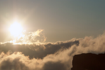 A golden sun descends behind soft clouds. The warm colors evoke feelings of tranquility,...