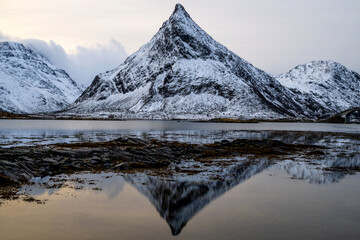 Fototapeta premium Reflection of snow-covered mountain range in a lake with calm water, Fredvang, Lofoten, Norway
