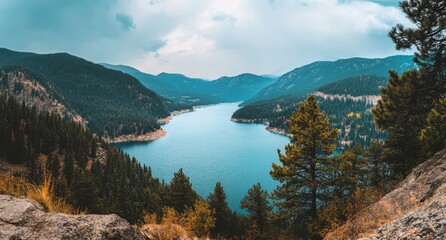 Obraz premium Serene Lake Surrounded by Majestic Mountains and Lush Forests under a Cloudy Sky in a Tranquil Natural Landscape