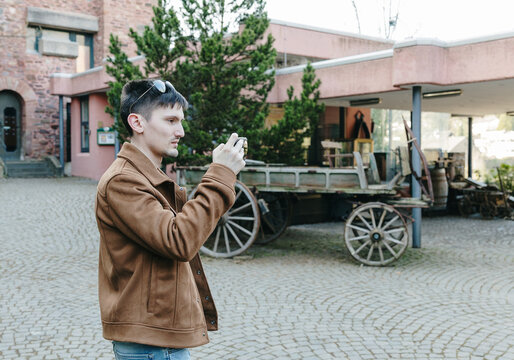 A guy takes a photo of a landmark on his smartphone in a castle.
