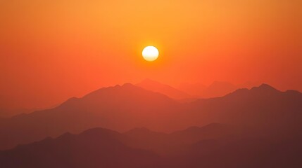 Obraz premium A vibrant orange sunset over the majestic mountain silhouettes in nature