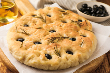 Delicious focaccia bread with olives and rosemary on table, closeup