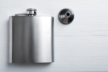 Hip flask and funnel on white wooden table, flat lay. Space for text