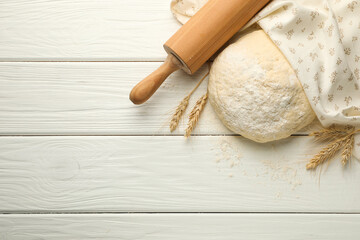 Fresh dough, rolling pin and spikes on white wooden table, flat lay. Space for text