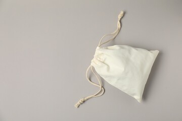 White cotton bag with ties on light grey background, top view. Space for text