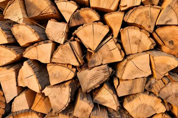 Selbstklebende Fototapeten Stack of logs in front of a wooden wall with emphasis on wood textures and patterns. Concept of rustic aesthetics and use of natural materials. © Masha