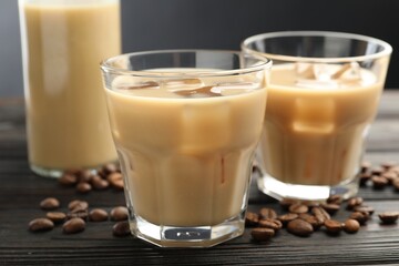 Coffee cream liqueur in glasses and beans on wooden table, closeup