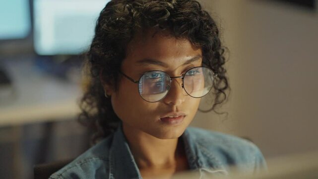 Closeup shot of Asian entrepreneur as she navigates her coder&rsquo;s journey, beautifully captured in a late-night, light-illuminated setting.