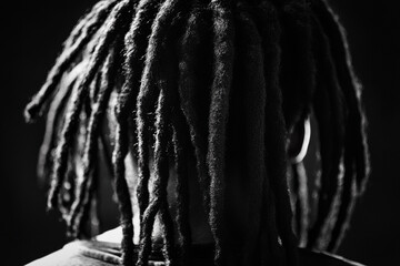 Close-up of individual with dreadlocks in a dark setting showcasing textured hair and style uniqueness