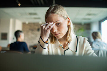 Stressed businesswoman working on laptop in modern office