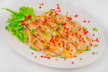 A plate of fresh steamed prawns garnished with chopped red and green chili, scallions, and lettuce, creating a colorful and appetizing seafood dish.