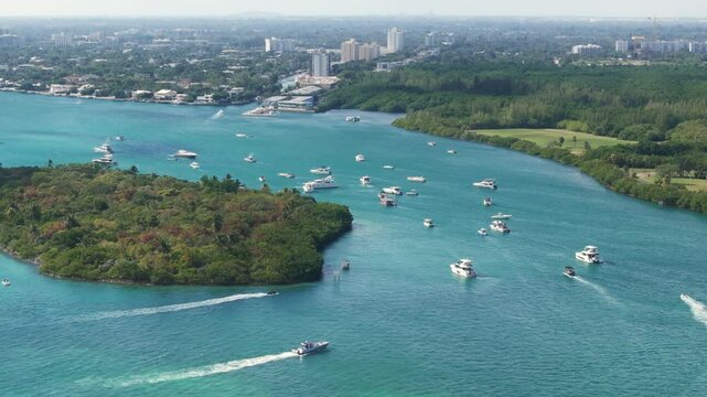 Enjoy the breathtaking aerial view of Haulover Sandbar, showcasing boats floating on the beautiful turquoise waters, surrounded by Floridas vibrant lush greenery and stunning coastline