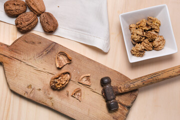 Zenithal plane of a cracked walnut and hammer on wooden paddle with shelled walnuts in bowl