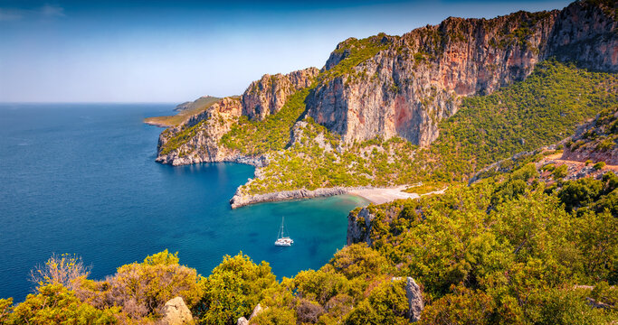 Astonishing summer view of Damos Beach with luxury yacht in the bay. Amazing morning scene of Peloponnese peninsula, Greece. Picturesque seascape of Myrtoan Sea. Vacation concept background.