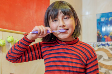 latin girl brushing her teeth in the bathroom of her home in la paz bolivia - latin america - dental cleaning concept