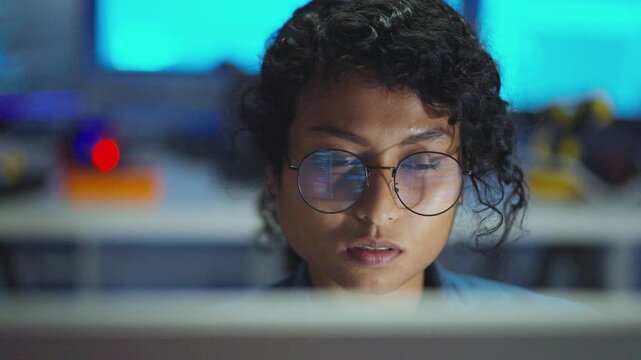 Focused on her computer, A Asian woman bridges technology and creativity, illuminating innovation in the dark.Focused on Asian woman analysis studying on data with multiple screen.