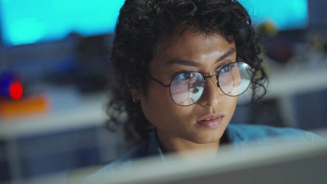 A woman, deeply focused on coding, illuminates her digital workspace late at night, showcasing expertise in a dynamic environment.