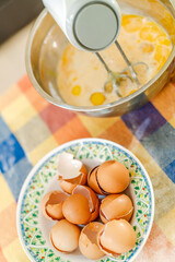 Pastry chef whisking eggs in bowl with eggshells nearby