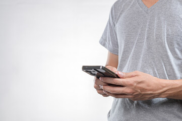 Person Holding Smartphone in Gray T-Shirt Against Neutral Background