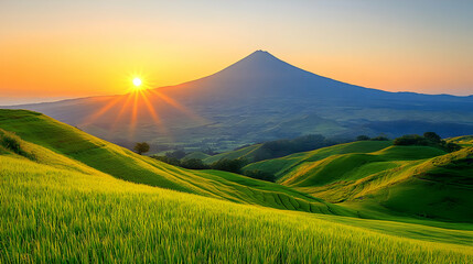 Fototapeta premium Vibrant Sunset Over Rolling Green Hills with Mountain Peak in the Distance with Warm Colors and Clear Sky in a Sunny Weather