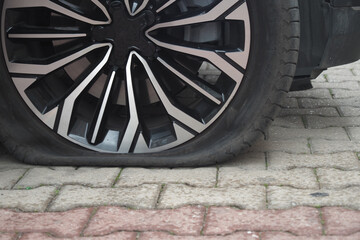 Flat tire on a stylish car parked on a cobblestone street