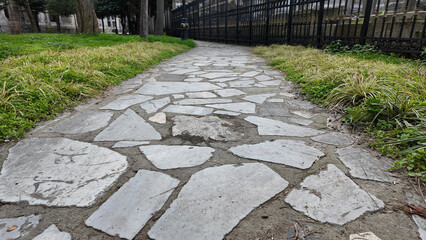 Stone pathway in a tranquil park surrounded by greenery and trees