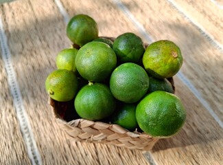 Fresh limes in a woven basket on textured background