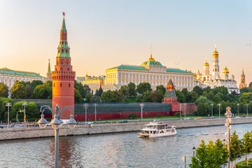 Selbstklebende Fototapeten View of Kremlin with Vodovzvodnaya tower, Grand Kremlin Palace from repaired Bolshoy Kamenny Bridge in Moscow city on sunny summer day. Cruise ship sails on the Moscow river © Dmitrii Potashkin