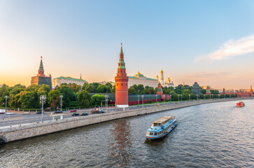 View of Kremlin with Vodovzvodnaya tower, Grand Kremlin Palace from repaired Bolshoy Kamenny Bridge in Moscow city on sunny summer day. Cruise ship sails on the Moscow river