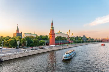 View of Kremlin with Vodovzvodnaya tower, Grand Kremlin Palace from repaired Bolshoy Kamenny Bridge in Moscow city on sunny summer day. Cruise ship sails on the Moscow river