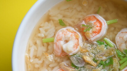 rice soup with shrimp in white bowl on yellow background