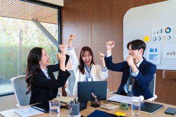 Excited startup team celebrating business success after achieving project milestones, fostering teamwork and motivation in a modern office environment focused on innovation and growth