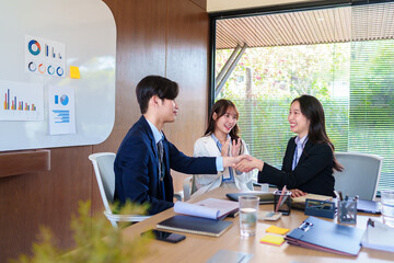 Confident young business professionals shaking hands to finalize a successful deal, celebrating partnership and agreement in a collaborative startup office environment