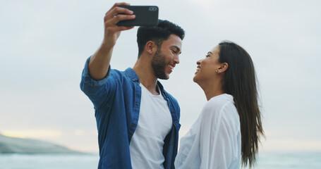 Obraz premium Beach, couple and happy selfie with love on honeymoon, holiday or bonding outdoor. Woman, man and together by sea for memory, romantic date and content with laugh on social media for profile picture