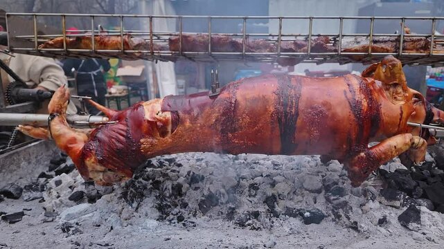 Pig on Spit and Pork meat Slow Roasting Over BBQ at food Festival SLIDE SHOT