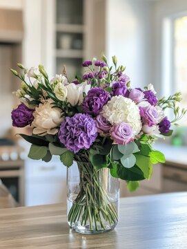 Beautiful arrangement of purple and white flowers in a clear glass vase on a kitchen countertop with a modern interior design background