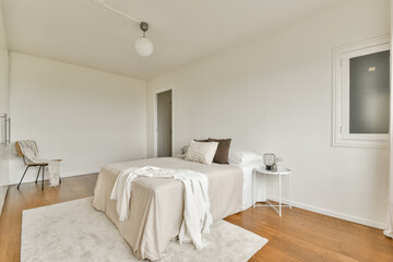 A bright and airy bedroom featuring a simple design, wooden flooring, a neutral color palette, and soft textures, creating a serene and inviting atmosphere.