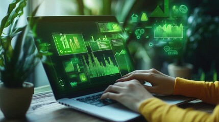 Woman using laptop with green data visualization interface showing charts graphs and financial information