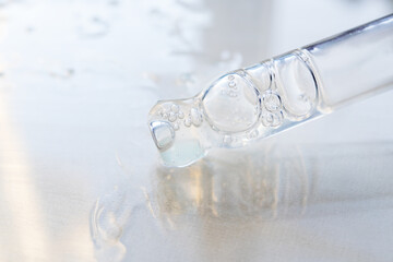 Pipette with essential oil on bottle blurred background