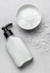 Magnesium flakes beside a dispenser for body cream on gray background