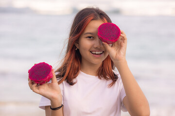 Portrait of  girl covering her eye with half a dragon fruit. Photoshoot with dragon fruits. Organic fruit concept. Bali